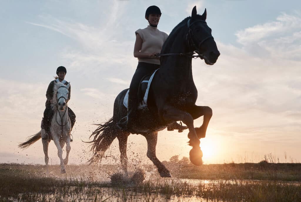 Some people go to therapy, we ride horses. Shot of two young women out horseback riding together.